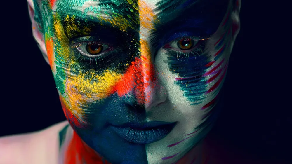 Rosto pintado com cores intensas, evocando símbolos e arquétipos